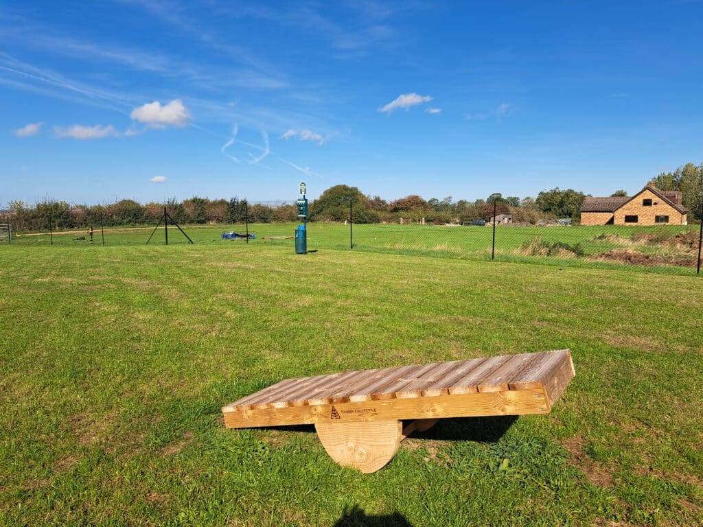 Wooden dog seesaw in the field at Foxholes Farm Dog Park