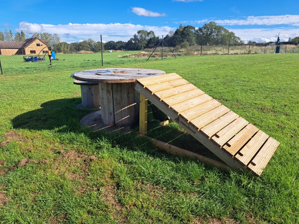 Wooden agility ramp and platform in the secure dog field at Foxholes Farm Dog Park